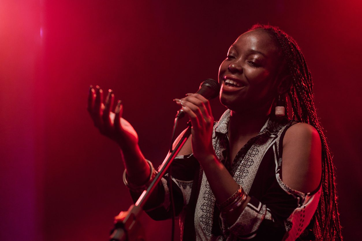 Singer performing on stage under red lights.