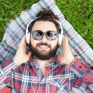 Man relaxing on grass with headphones.