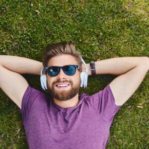 Man relaxing on grass with headphones.